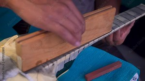 Luthier repairing an electric guitar, fret grinding, fretboard sanding and polishing, musical instrument workshop
