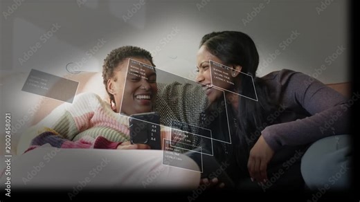 Two women on sofa sharing phones tapping screens moving floating UI panels sharing joy for tech