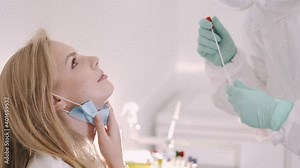 Female doctor in a protective suit taking a nasal swab from a person to test for possible coronavirus infection. Nasal mucus testing for viral infections. Medical Concept. Covid