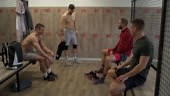 Small group of men changing clothes in gym locker room