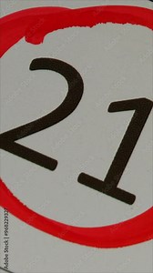 21 - Marking the date in the calendar with a red marker. The twenty-first day of the month, the hand encircles date 21 on the calendar. Vertical.