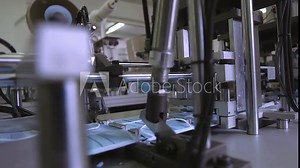 Manufacture of medical masks. Medical mask on conveyor belt in the workshop of factory for production of medical clothing. Production of disposable medical clothing for protection against the virus.