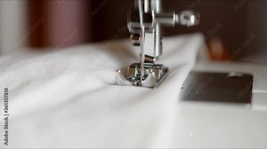 Seamstress shows a master class in sewing. Close-up of sewing Machine for sewing light fabric. Slow motion sewing machine needle sewing fabric white color