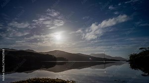 time lapse of a yacht and boat under clouds over mountains over the water in a national park and beautiful rock mountain above the ocean in a national park