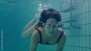 beautiful woman swimming underwater in pool smiling waving hand attractive female enjoying swim in clear water 4k