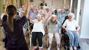 Carer Leading Group Of Seniors In Fitness Class In Retirement Home