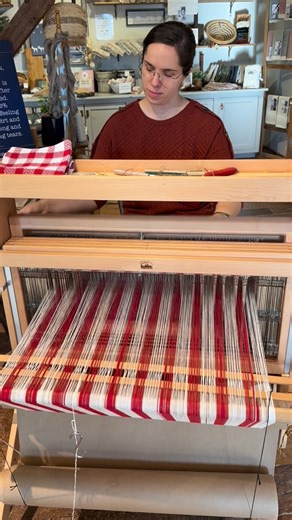 Homestead Fibercrafts on Instagram: "You all know Deborah, you will see her weaving or winding out warps in a lot of our posts. Today it’s a rosepath patterned checked towel, so there are frequent color changes. Sometimes you’ll even catch her spinning on her Turkish spindle which she keeps under the counter for those “behind the counter” moments and if you take a rigid heddle class, or drop spindle class, she will also be your teacher. Deborah pops up in a lot of places and she’s always there w