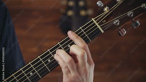 close up mans hand taking chords on acoustic guitar slow motion