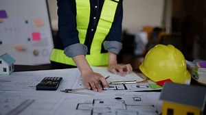Close up of hands working and calculations on paperworks and floor plan drawings about design architectural and engineering for houses and buildings.