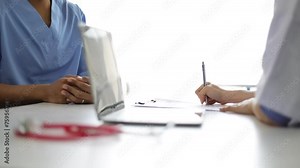 Female doctor talking with male patient in examination room at hospital.