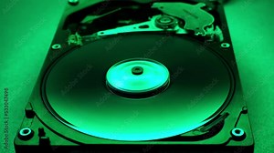 Disassembled hard disk drive in the dark with a green light. Start and stop of hdd, how it works. HDD repair, Data Recovery, electronic technologies.