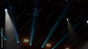 Vibrant stage lights beam across a dark venue of rock concert. Blue and white stage lighting illuminates the night during a live performance. Light effects in the darkness of a live music event Stock Video