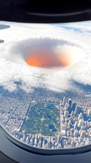 Earth Impacts on Instagram: "Massive Sinkhole Spotted Over New York — near Central Park Plane window view over New York at sunrise, catching a giant sinkhole through cloud breaks. The bottom glows subtle orange-red. Slow, shaky, difficult to frame fully, realistic amateur footage. #earthimpacts #fblifestyle #newyork #sinkhole #cloudscape #aerialview #amateurfootage #surreal"