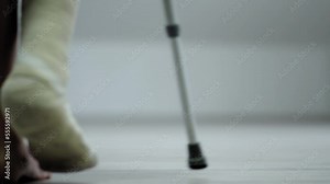 Close-up of woman leg in plaster cast using crutches while walking.