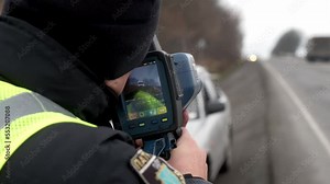 road police officer using a mobile radar on the highway. Speed control radar controlling car speed, monitoring highway traffic violations. Police traffic speed control camera