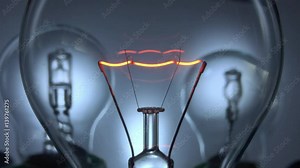 Close up of a filament in a light bulb with two halogen bulbs in the background.The light switches on slowly and then changes from positive to negative and back again before switching off slowly.