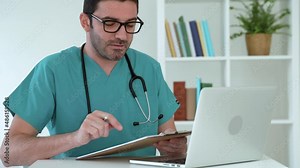 Male Doctor in blue uniform video calling distant patient on laptop. Gynecologist talking to client using virtual chat showing medical reports and ultrasound scans. Distance Physician consultation. 4k