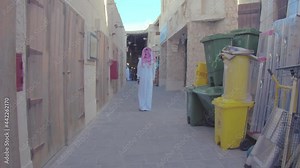 Back View Of An Arab Man In White Thawb And Agal Passing By A Pet Shop In Souq Waqif, Doha, Qatar. handheld shot