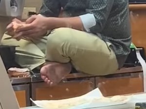 Worker sits cross-legged with bare feet on food counter