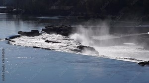 Water flows in video of Willamette Falls waterfall on the Willamette River in Oregon City, Oregon. Spray rises. The falls generates electric power and once powered several paper mills on the banks.
