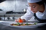 Chef mujer guarnición de flores en el plato en la cocina | Foto Premium