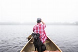 Bela foto de um cão preto e um macho navegando em um pequeno barco no ...