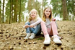 Two cute young sisters having fun during forest hike on beautiful early ...