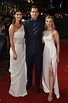 two women and a man standing on a red carpet