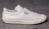 a white puma tennis shoe with blue trim