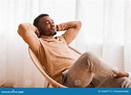 Black Guy Relaxing Sitting on Modern Chair Against Window Indoor Stock ...