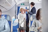 Flight attendant greeting passengers boarding airplane - Stock Photo ...