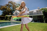 Happy little girl playing with hula hoop in the backyard. Smiling girl ...