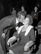 an old photo of a man kissing a woman on the cheek in front of other people