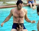 a man with no shirt sitting on top of another man in a swimming pool