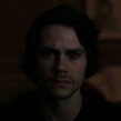 a man with dark hair and eyes staring at the camera in a dimly lit room