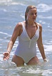 Margot Robbie manages a stylish wipe out surfing in a white one piece ...