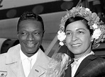 a man and woman standing next to each other in front of an airplane ...