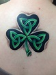 a shamrock tattoo on the back of a woman's shoulder