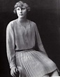 an old black and white photo of a woman in a pleated dress sitting on a ...