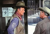 In Rio Lobo (1970), John Wayne’s character stands next to a Wanted ...