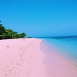the beach is pink and clear with footprints in the sand, trees on ...