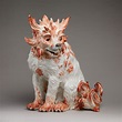 an orange and white dog figurine sitting on top of a gray surface with ...