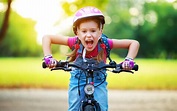 happy cheerful child girl riding a bike in Park in nature - Realities ...