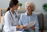 Young woman doctor consult happy old grandmother patient hold papers ...