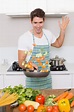 Hombre alegre lanzando verduras en la cocina | Foto Premium