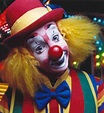 a close up of a clown's face with lights in the background