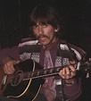 a man with a mustache playing an acoustic guitar