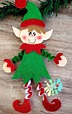 an elf ornament hanging from a christmas tree with red and green glitters
