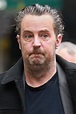 Matthew Perry looks dishevelled with messy slicked back hair and an ...