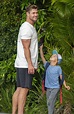 Super dad! A barefoot Chris Hemsworth shows off his insane biceps as he ...